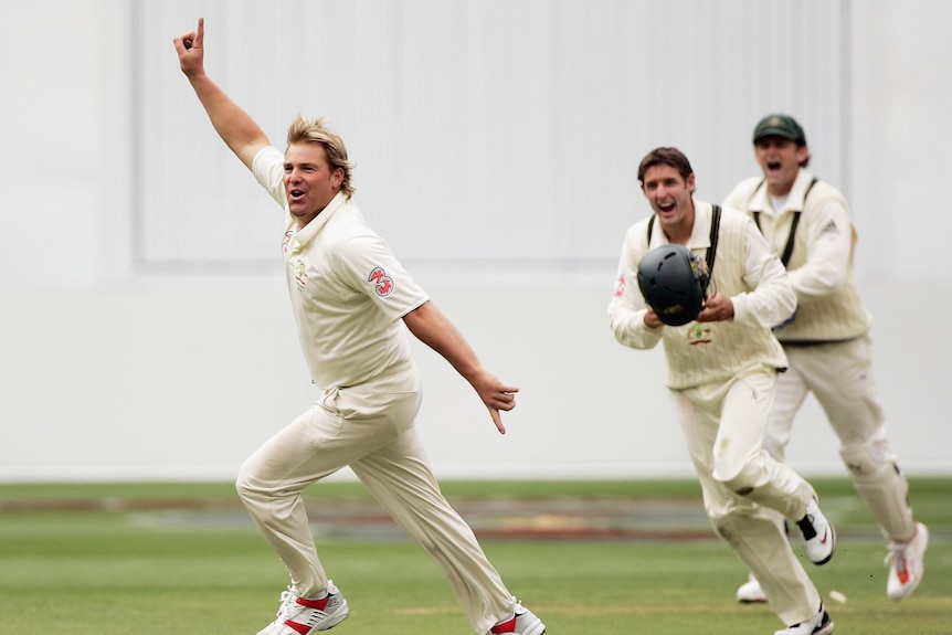 Shane Warne runs away from Michael Hussey and Adam Gilchrist as he celebrates his 700th Test wicket, against England at the MCG.