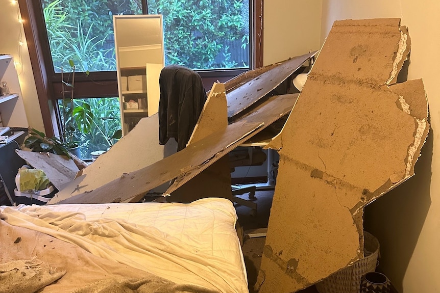 Chunks of bedroom ceiling collapsed onto a bedroom, dust and debris scattered around,
