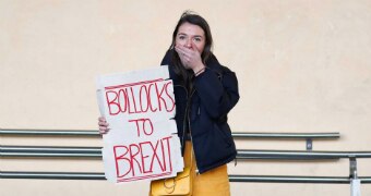 A woman holds a sign saying, "Bollocks to Brexit".