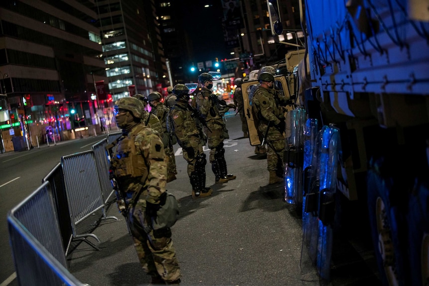 Members of the US National Guard stand on a Philadelphia street at night.