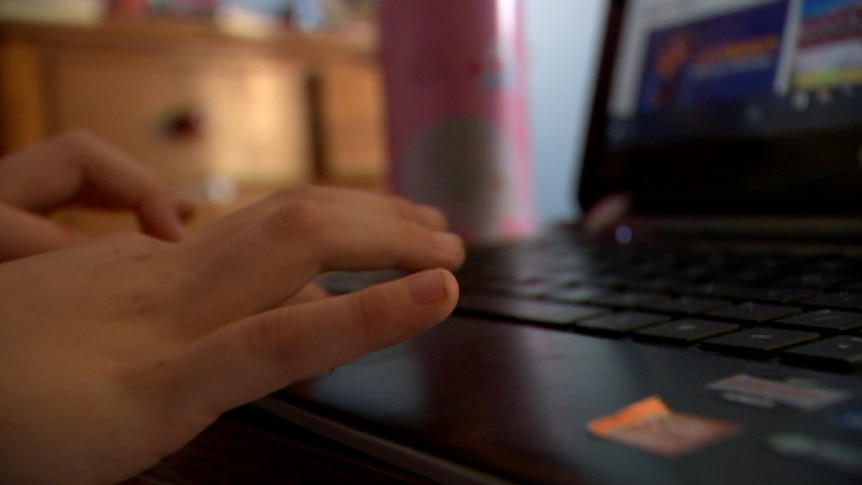 The hands of a child typing at a laptop
