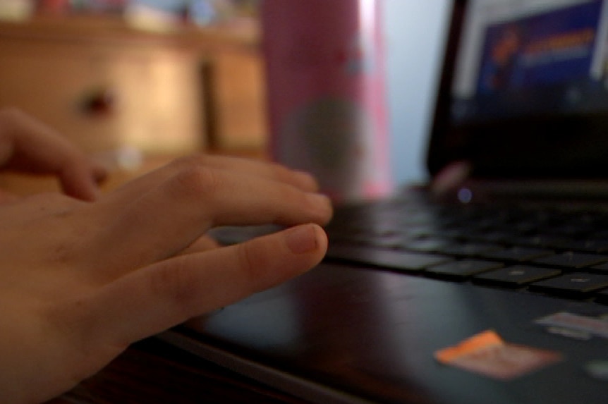 The hands of a child typing at a laptop