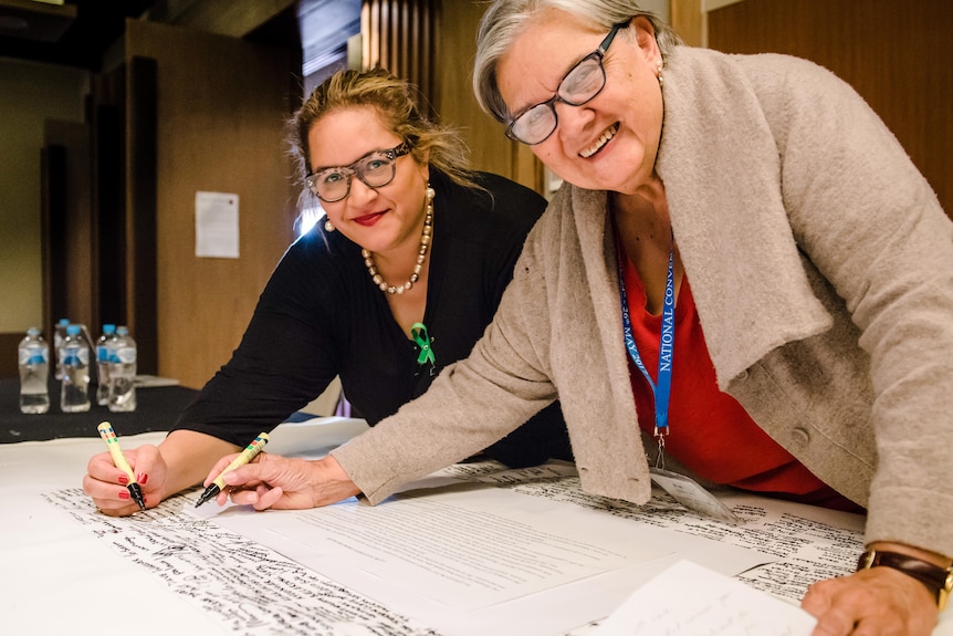 Two women signing Uluru Statement from the Heart