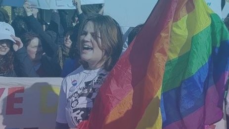 A woman holds up a rainbow flag.