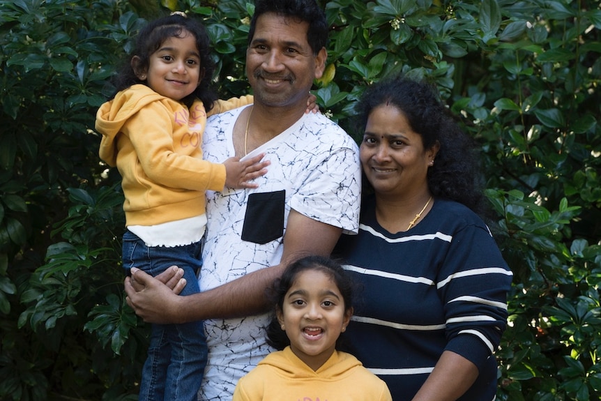Priya, Nades, Kopika and Tharnicaa standing in front of greenery, smiling.