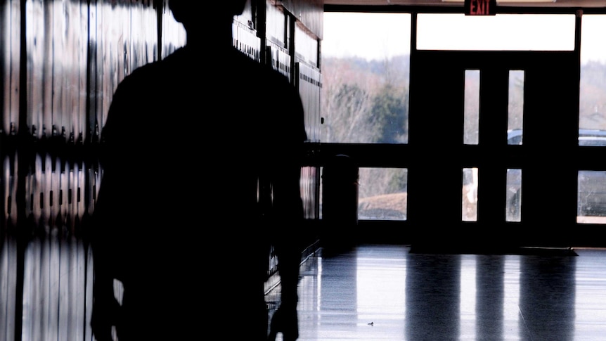 A student stands in a school hallway.
