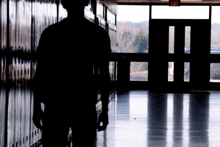 A student stands in a school hallway.