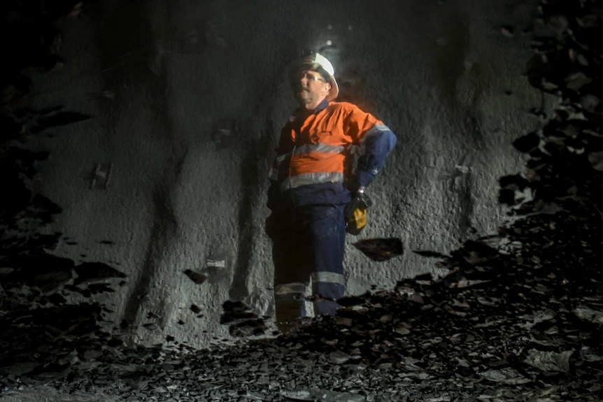 A miner's reflection in a puddle, underground.