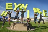 ABC Heywire competition winners jump in front of parliament holding giant letters that spell Heywire.