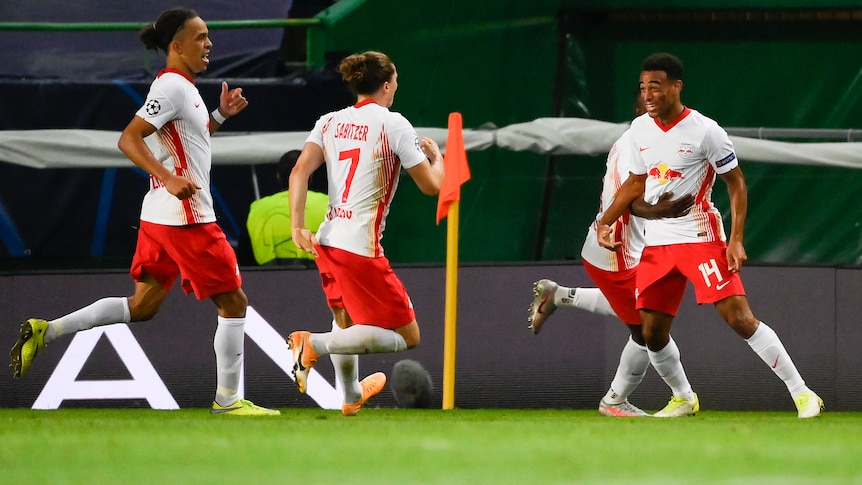 RB Leipzig players wearing white shirts and red shorts with white socks run to each other
