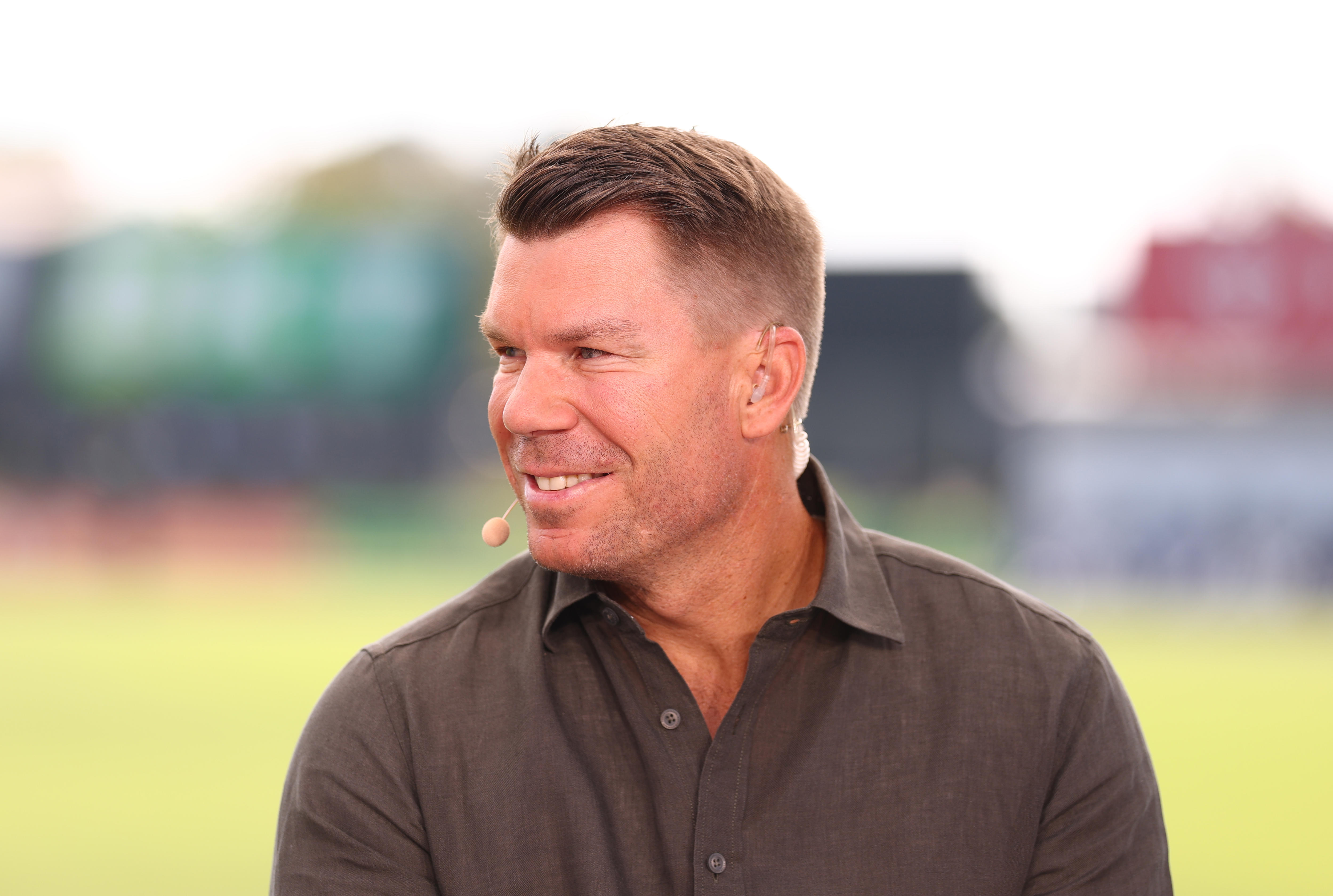 A close up shot of a person commentating a cricket game with microphone near mouth