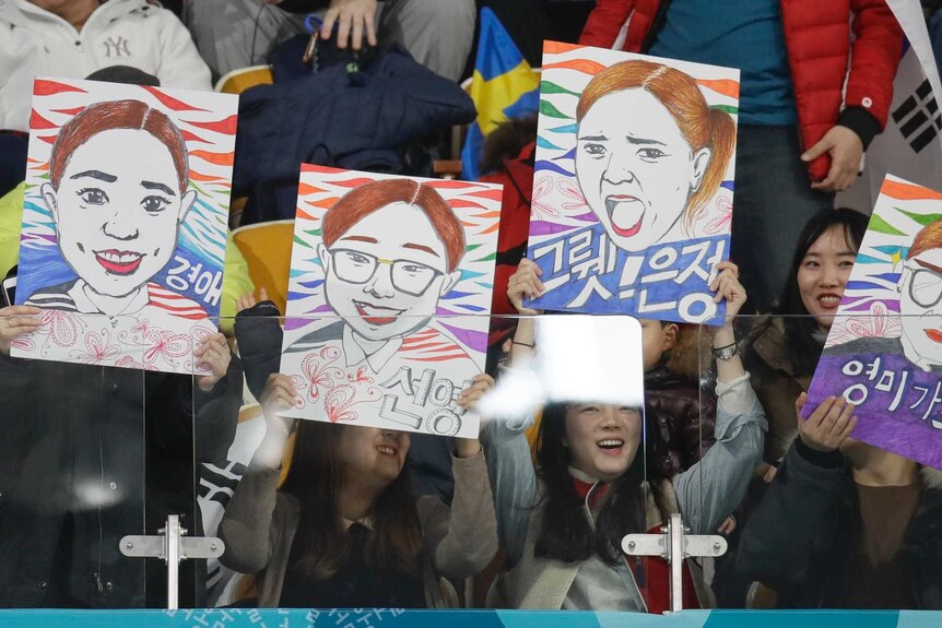 Fans hold up portraits of the Garlic Girls.