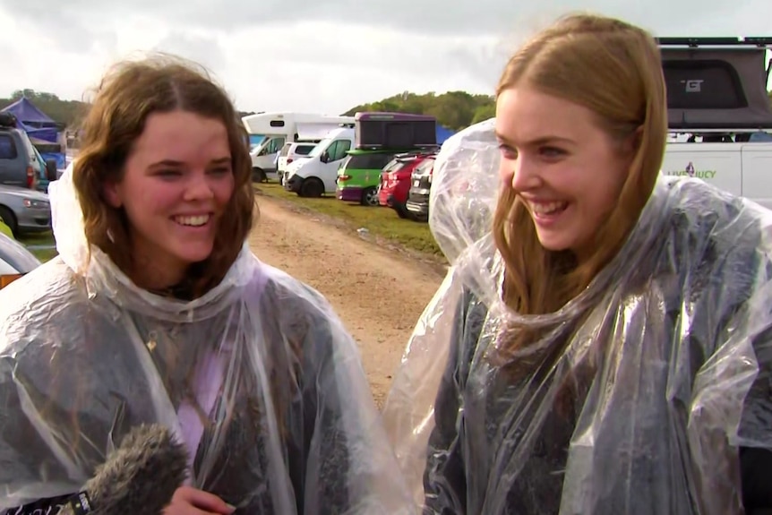 Two girls wearing rain jackets smiling at the Splendour campground. 
