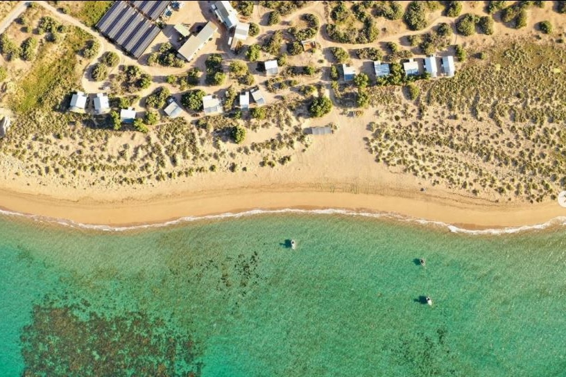 A shot from the air of the ocean , sand and holiday houses