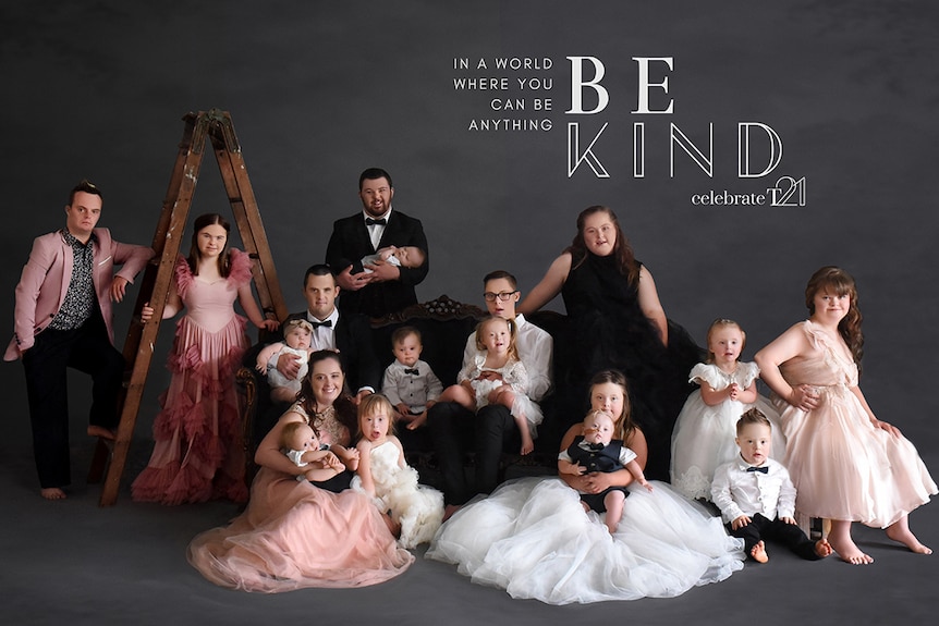 People with Down syndrome in formal and semi-formal wear pose while standing or sitting on a couch with a black wall.