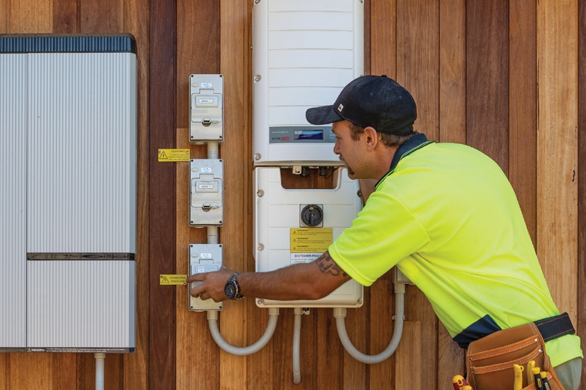 A tradesman in bright yellow working on a power meter.