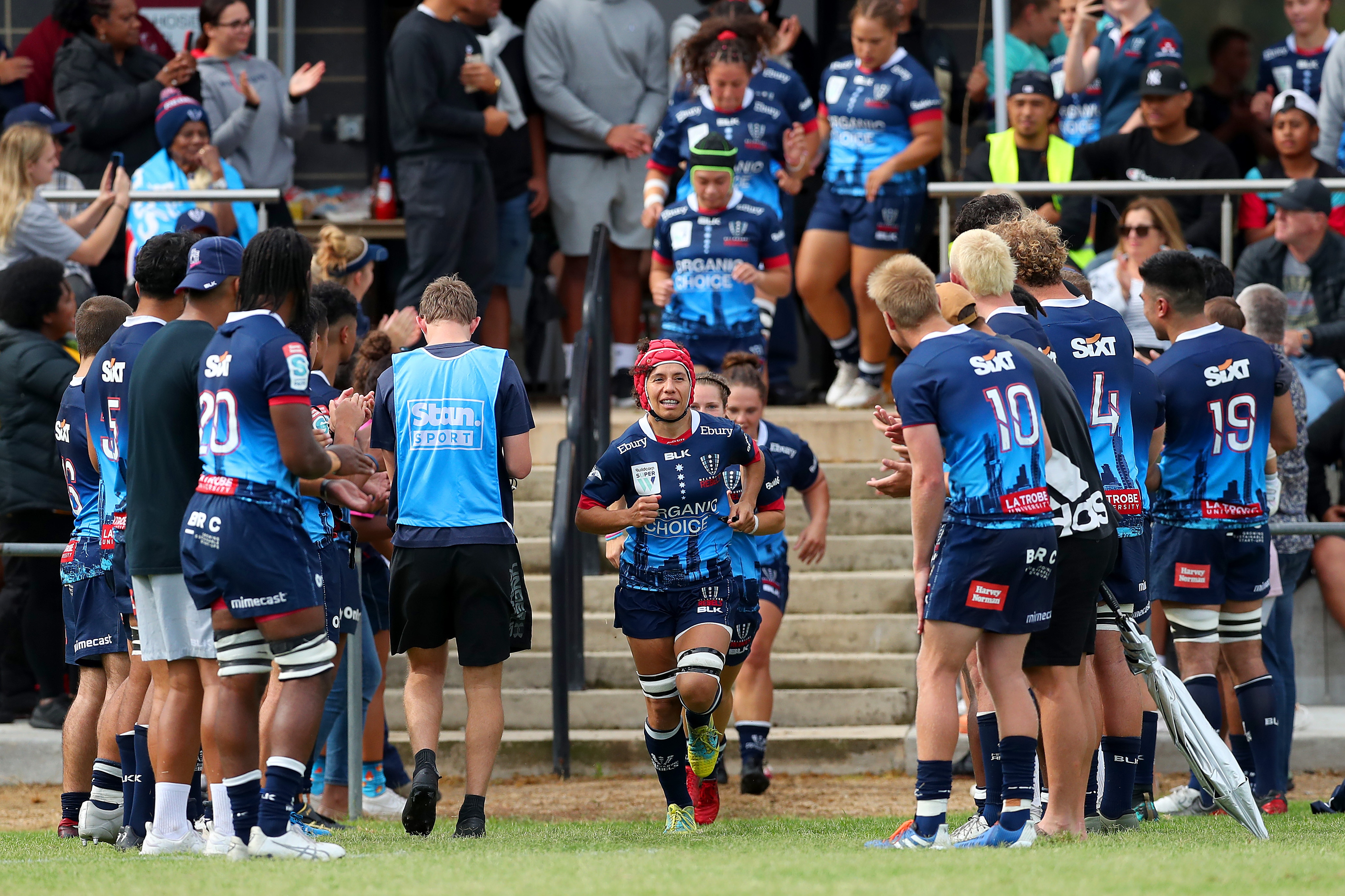 Melanie Kawa (c) of the Rebels leads the Rebels out to the field.