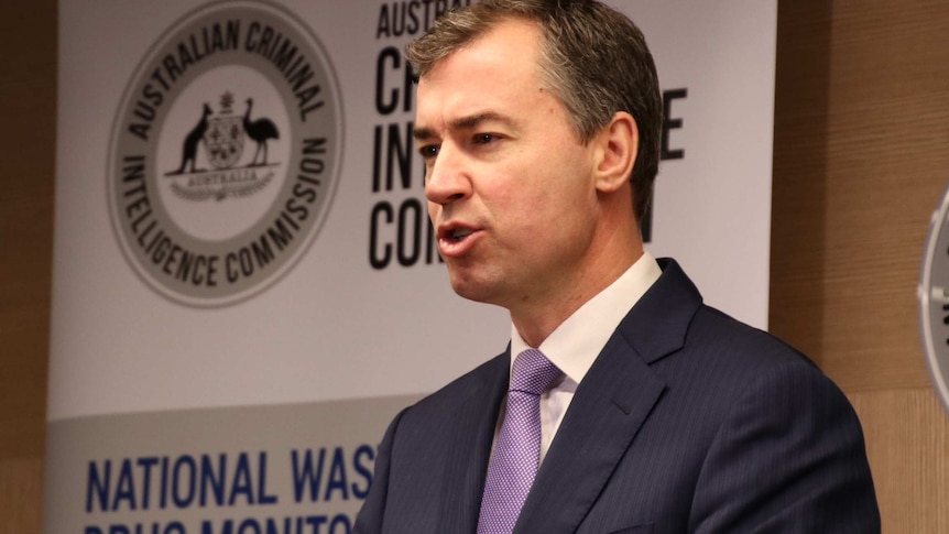 A mid shot of federal Justice Minister Michael Keenan standing indoors speaking at a media conference wearing a suit and tie.