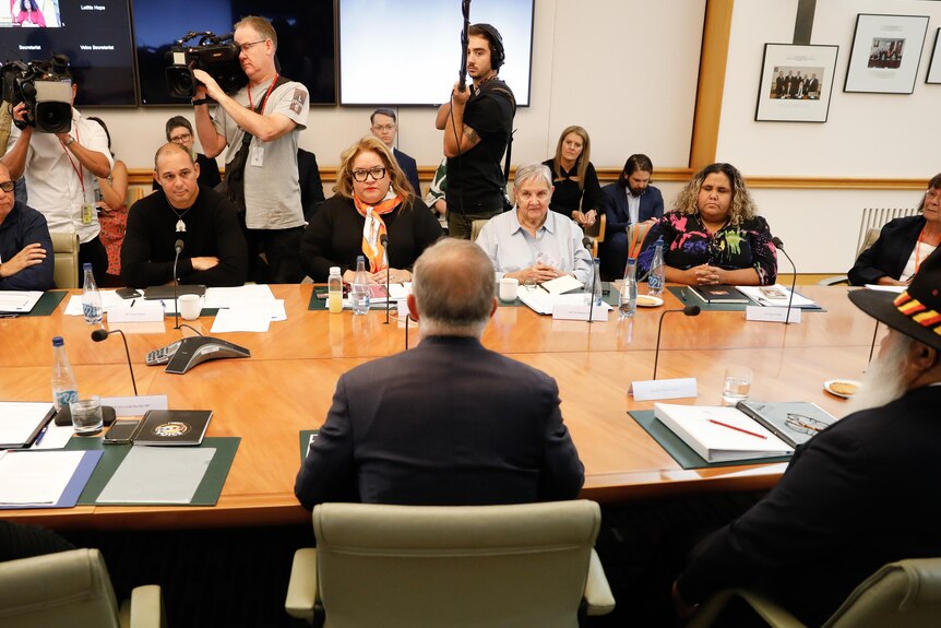Antony Albanese sits facing a group of Indigenous people over a conference room table. 