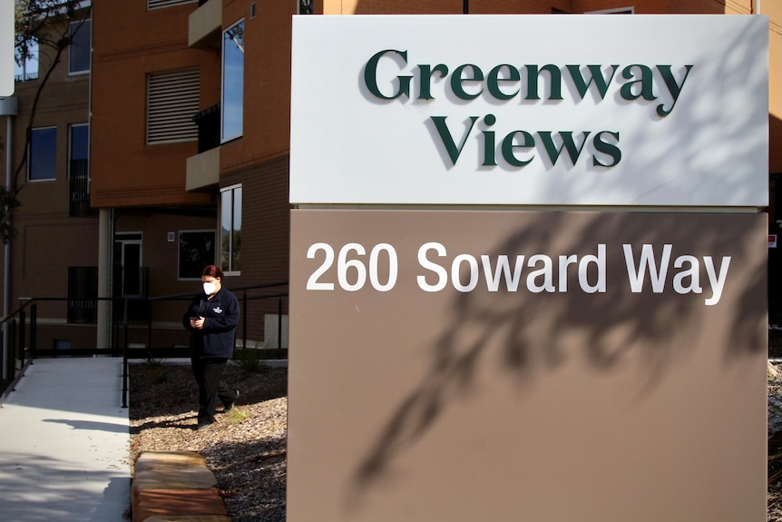 A sign that reads Greenway views 260 Soward way with someone wearing a facemask nearby