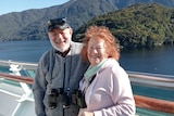 Jane and John Newson, in their 70s, smiles at the camera.