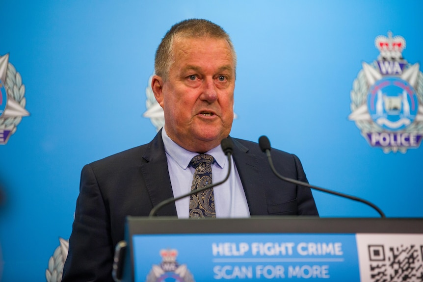 A mid-shot of WA Police Detective Superintendent John Hutchison speaking at a police media conference indoors.