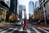 a woman in a face mask walks across a pedestrian crossing in a street in Beijing