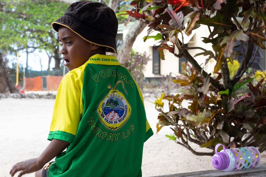 A young boy wearing a Poruma school t-shirt.