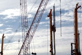 Cranes and construction equipment stand at a construction site