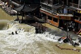 Flood waters sweep through a street, sweeping onto street