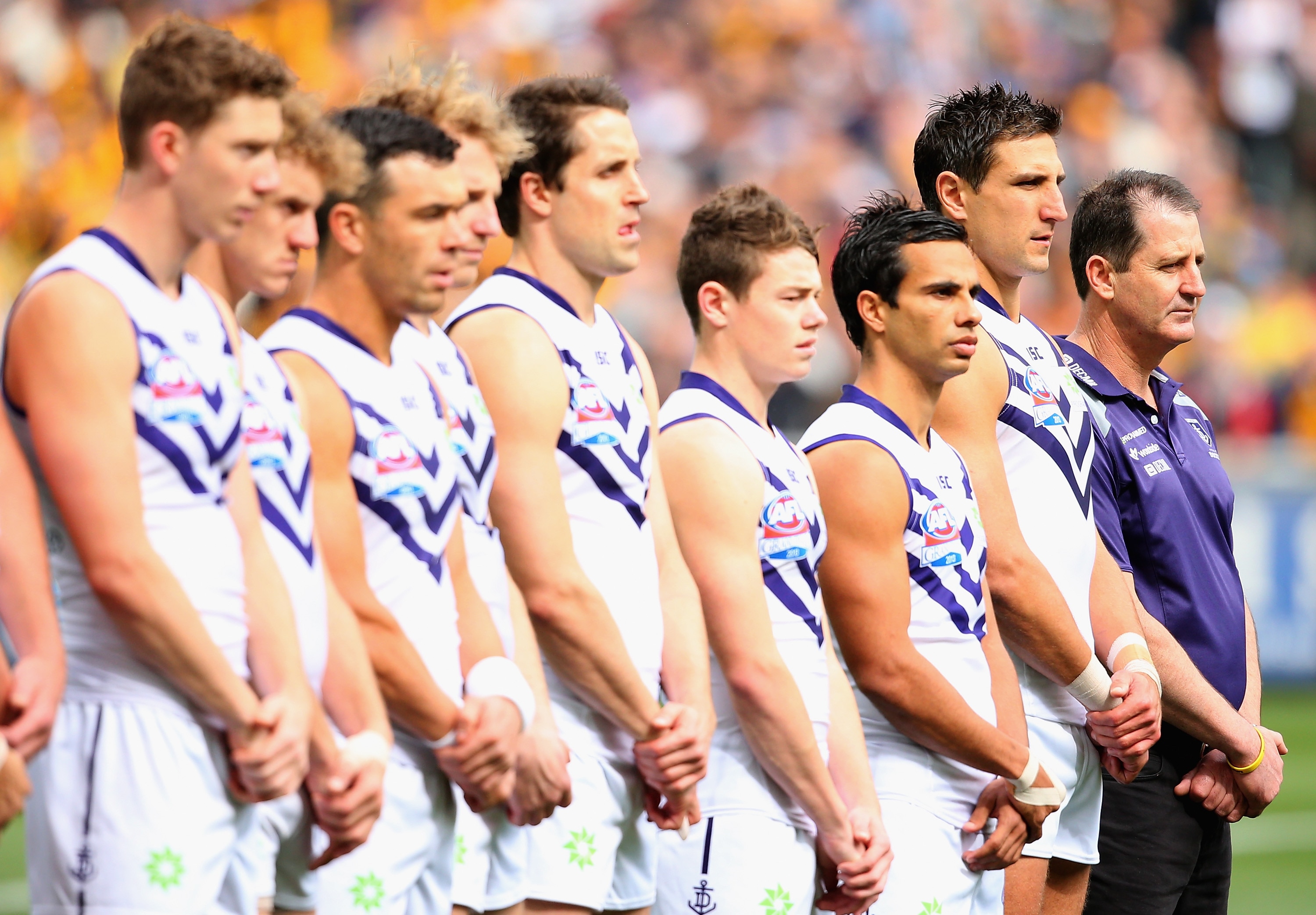 Lachie Neale standing next to Fremantle teammates and coach