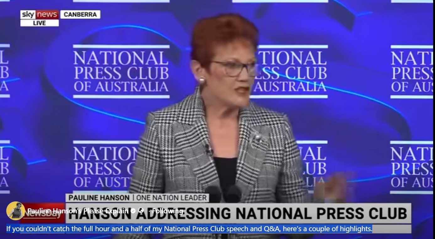 A screenshot of a woman with red hair, wearing glasses, speaking.