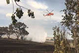 A helicopter bombs the Sutton fire with water.