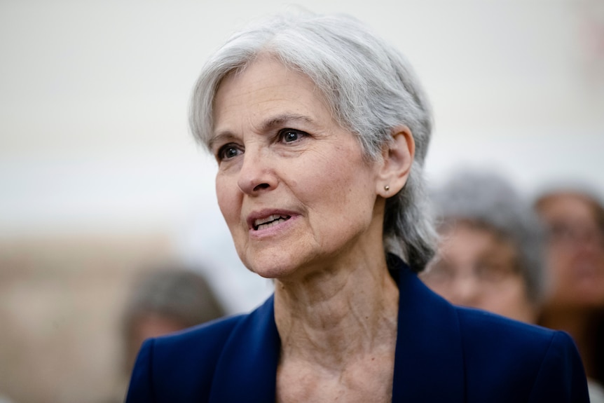 A close-up photo of an older white woman with grey hair in a blue suit looking serious.
