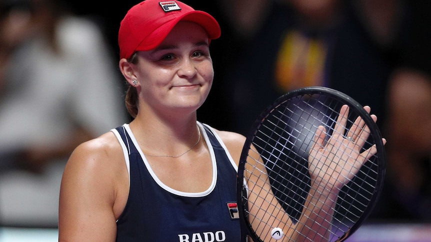 Ash Barty smiles and claps on her racquet while looking at the crowd.