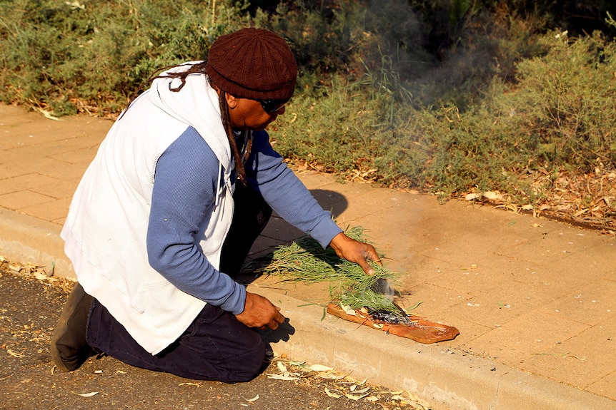 Braydon Kantjira lights a smoke fire to cleanse cases containing sacred objects being returned to Aboriginal people.