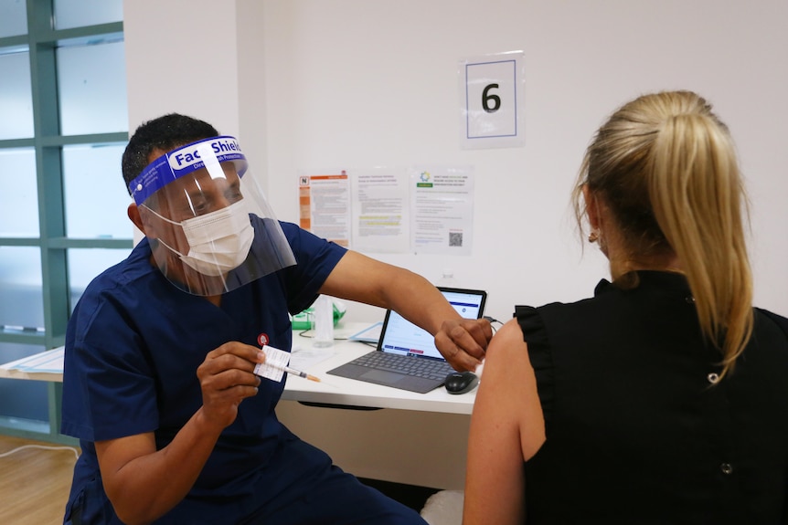 Male nurse vaccinating a woman