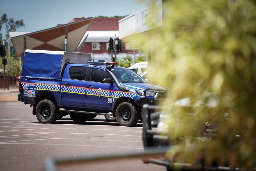 A blue NT Police paddy wagon parked on a main street in the Darwin CBD, on a sunny day.