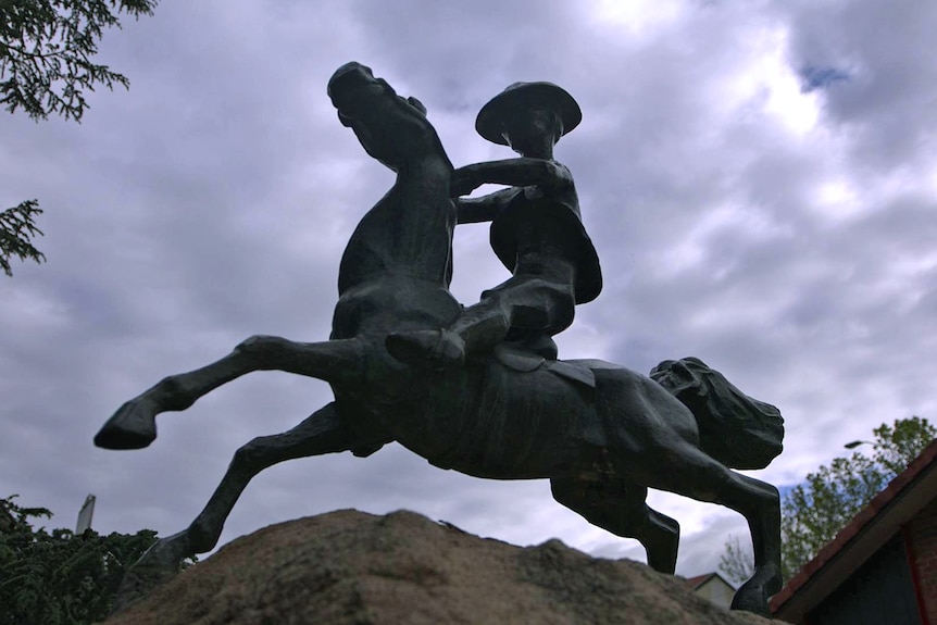 A statue of a stockman riding a brumby.