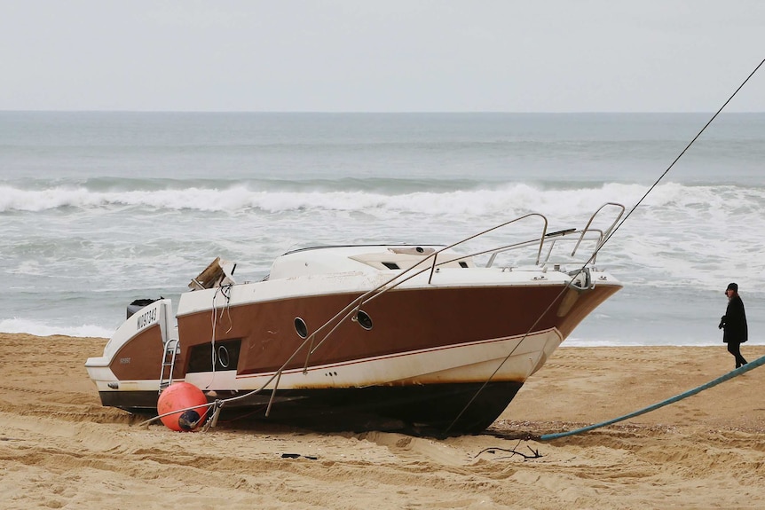 Image of a damaged speedboat washed ashore on a beach in France