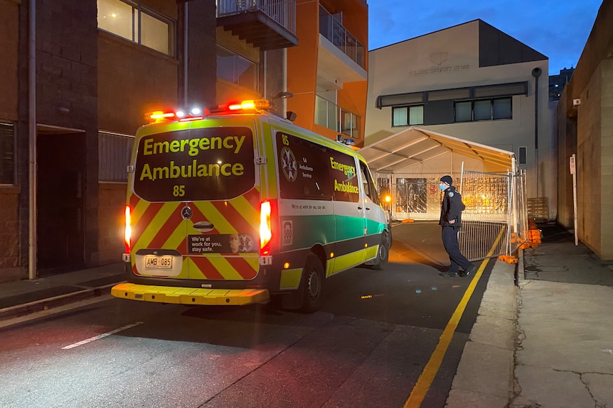 An ambulance near a hotel in the dark on a wet night