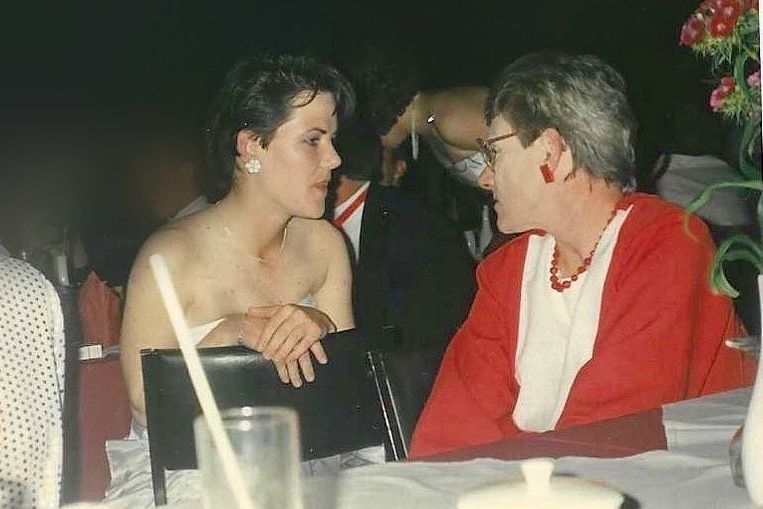 A young woman and a grey haired woman are both seated as they speak to one another