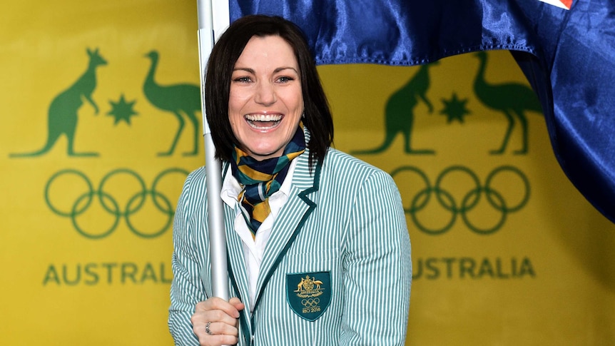 Anna Meares smiles with the Australian flag after being announced as Flag Bearer