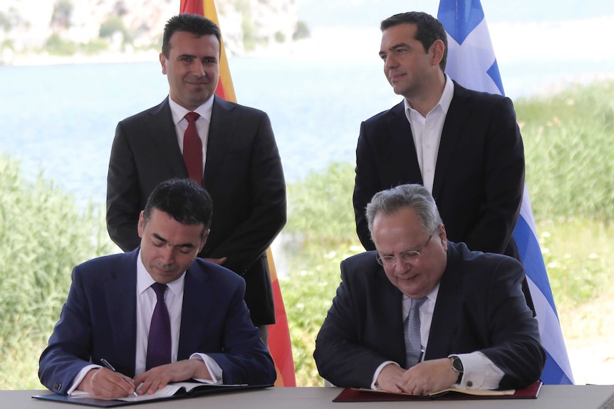 Prime ministers of Greece and Macedonia stand behind their foreign ministers as they sign accord