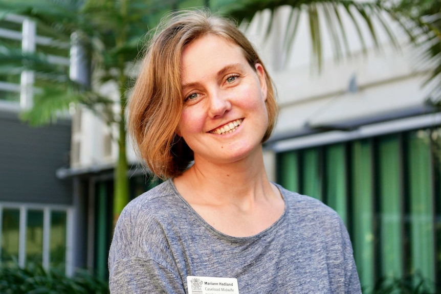 Blonde woman smiling at camera and wearing a grey shirt and hospital name tag that reads 'Mariann Hadland Caseload Midwife'.