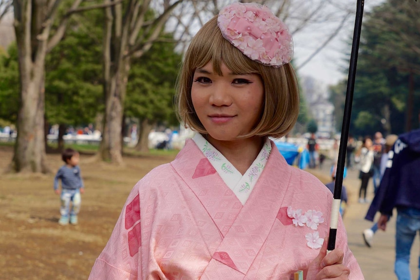 Girl in pink kimono adorned in cherry blossom flowers