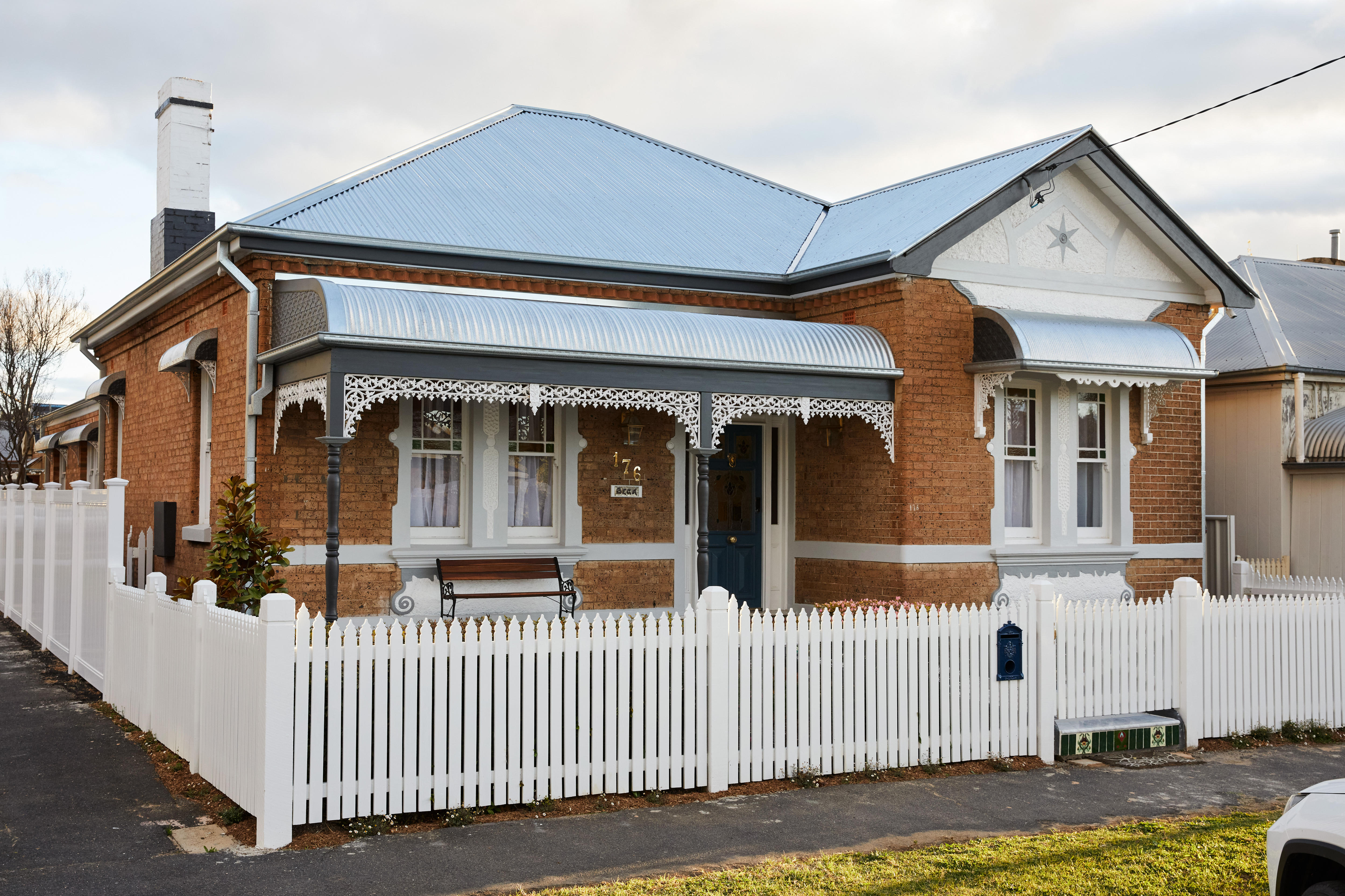 Вид на улицу дома федерации с серебряной крышей и недавно отреставрированным крыльцом с белым забором