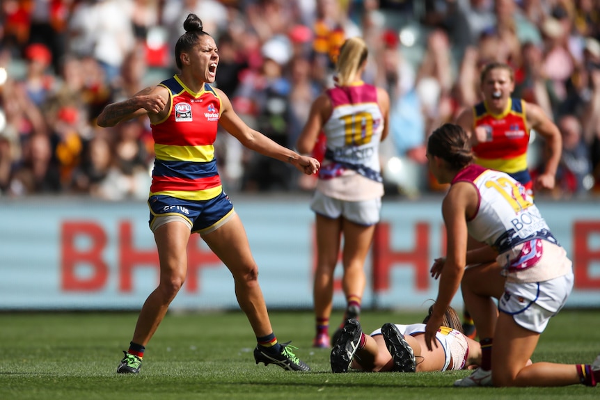 An Adelaide player celebrates as Brisbane players lie on the ground