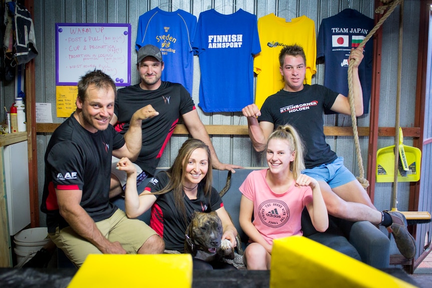 Arm wrestlers Ryan McLaren, Toby Whateley, Shaleigh Maldonado-McLaren, Tayla Nash and Rohan Symens with fists pumped in a gym.