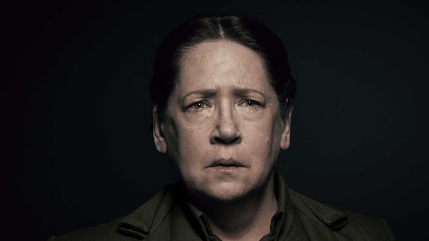 Ann Dowd, in character as Aunt Lydia, stares forlornly